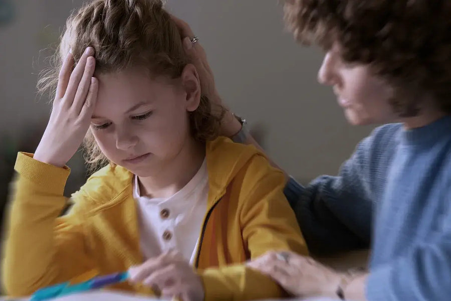 bambina che studia su un banco di scuola aiutata da docente
